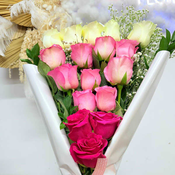 Bouquet of pink and white roses wrapped in white paper with a pink ribbon