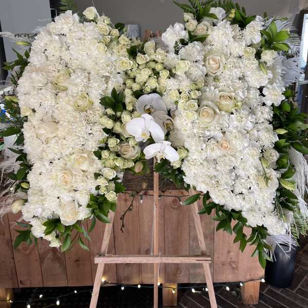 Large white floral spray on an easel with roses and orchids
