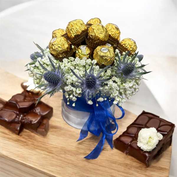 Chocolate gift arrangement with gold-wrapped candies and blue thistle flowers
