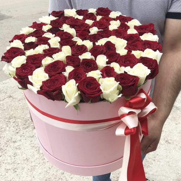 Round pink hat box filled with red and white roses and tied with red and white ribbons