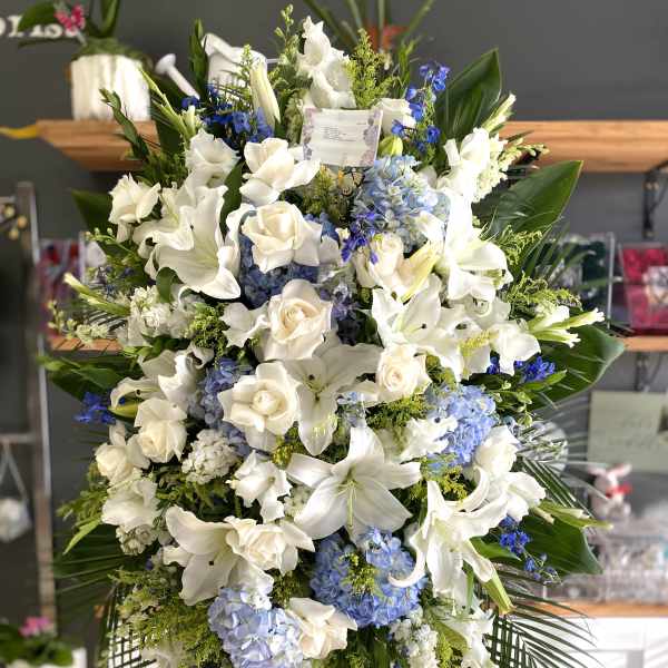 Large white and blue floral standing spray on an easel