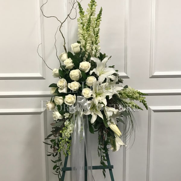 Tall white floral standing spray with roses and lilies on an easel
