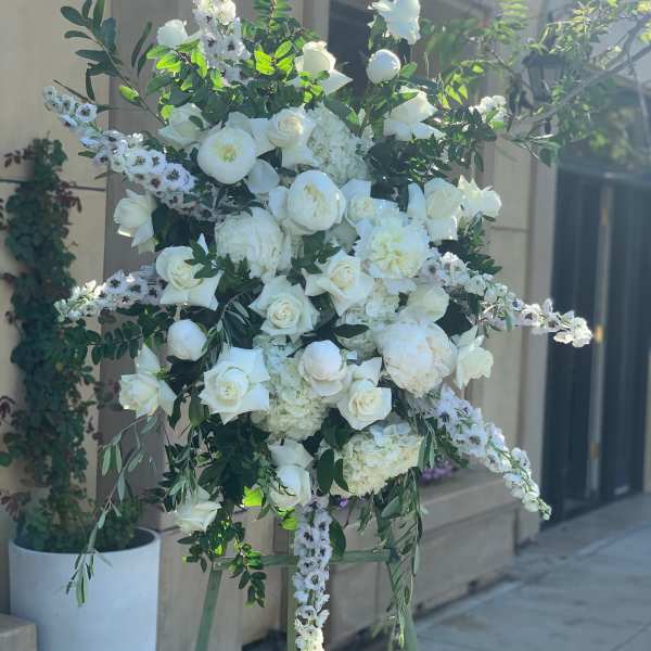 Large white floral standing arrangement on an easel