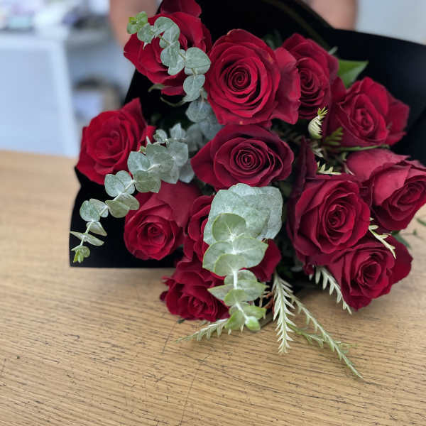Bouquet of red roses with eucalyptus wrapped in black paper