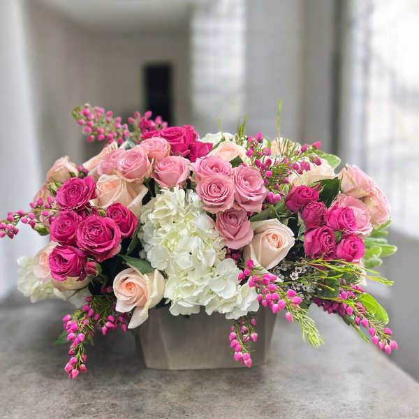 Pink and white rose arrangement in a low square vase