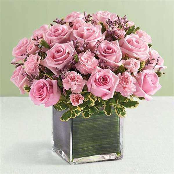 Pink roses and carnations arranged in a square glass vase