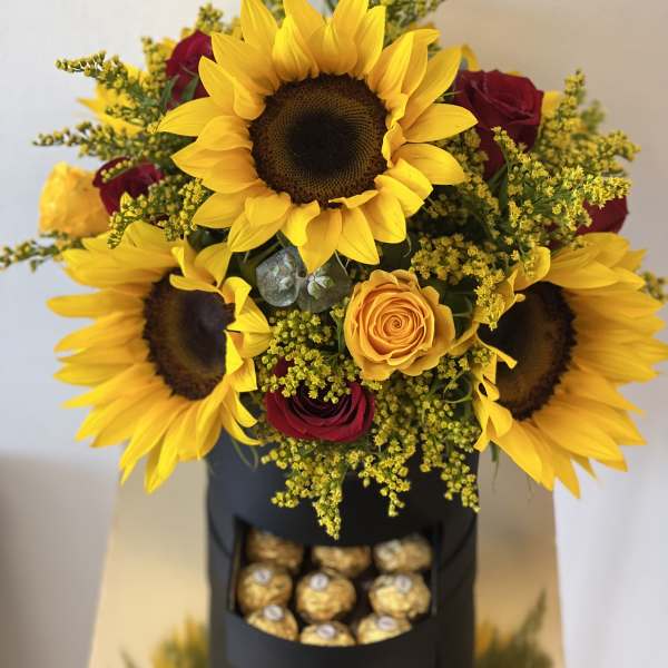 Bouquet of sunflowers and red roses with a box of chocolates