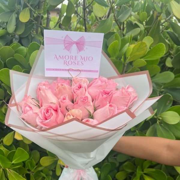 Bouquet of pink roses wrapped in white paper with a pink ribbon