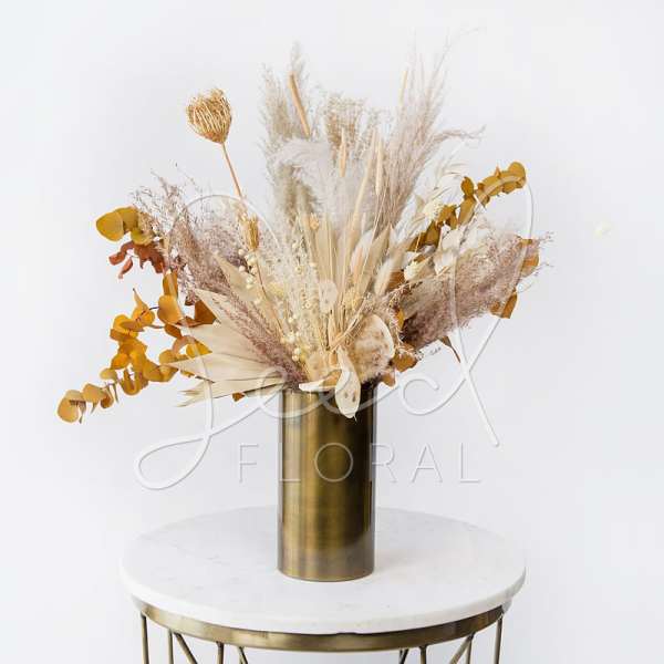 Dried floral arrangement in a gold vase with beige and mustard tones