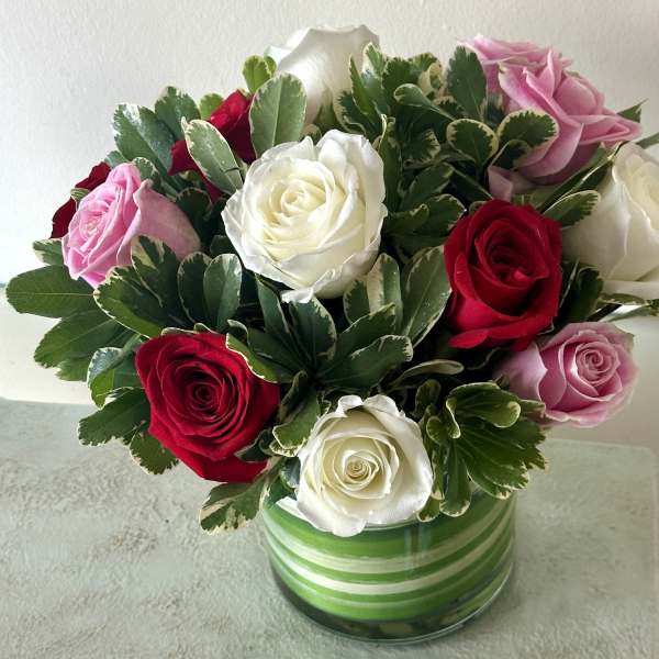 Bouquet of red, white, and pink roses in a striped glass vase