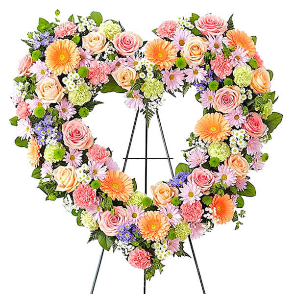 Heart-shaped floral wreath on a black easel with pink, peach, and orange blooms