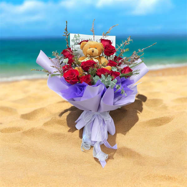 Bouquet of red roses with a teddy bear in lavender wrapping