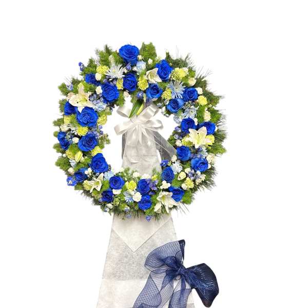 Blue and white floral funeral wreath on a stand with ribbon