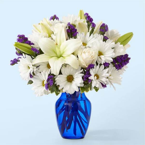 White lilies and daisies in a blue glass vase