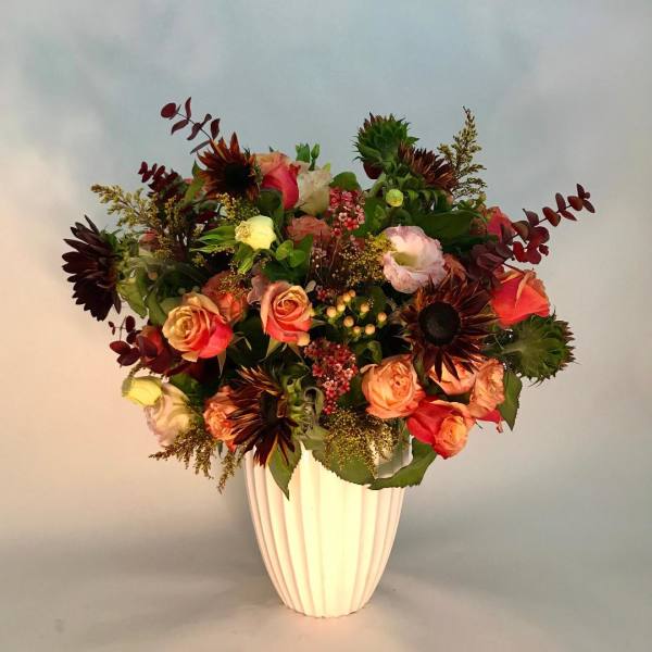 Mixed bouquet of roses and sunflowers in a white vase
