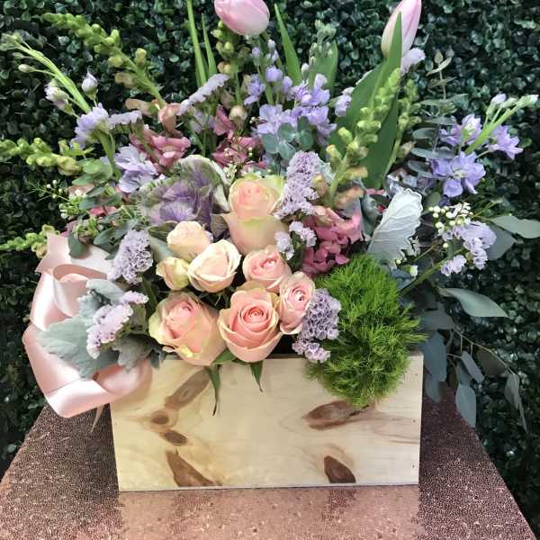 Pastel bouquet with pink roses and tulips in a wooden box