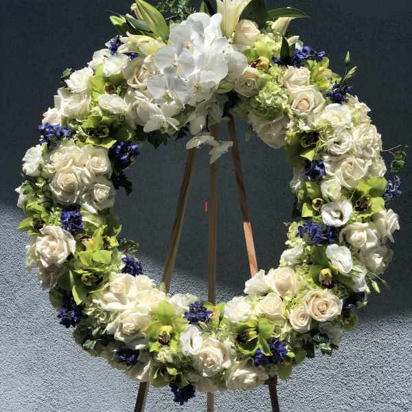 Large floral wreath on a wooden stand with white roses and orchids
