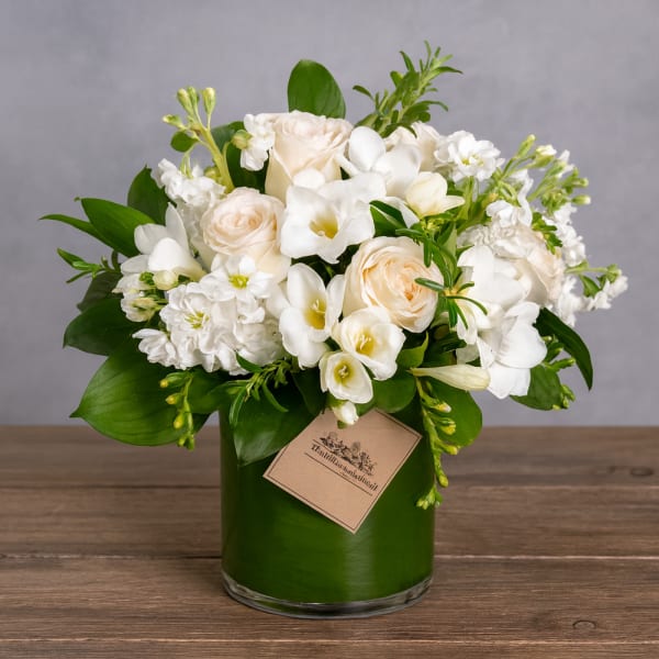 White and cream floral arrangement in a green glass vase