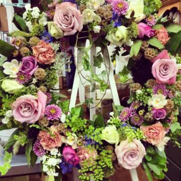 Floral wreath with pink roses and purple blooms on a white easel