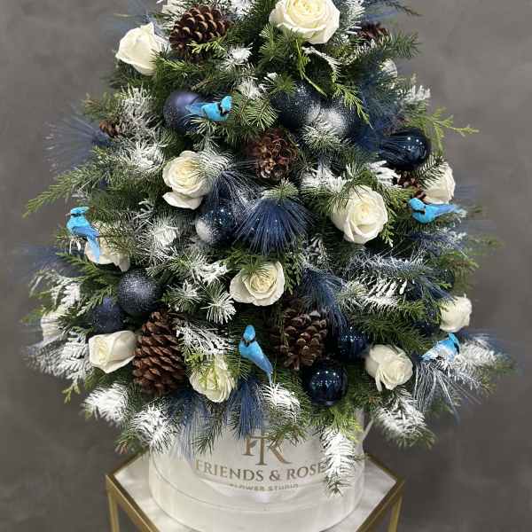 Christmas tree arrangement with white roses, pinecones, and blue ornaments