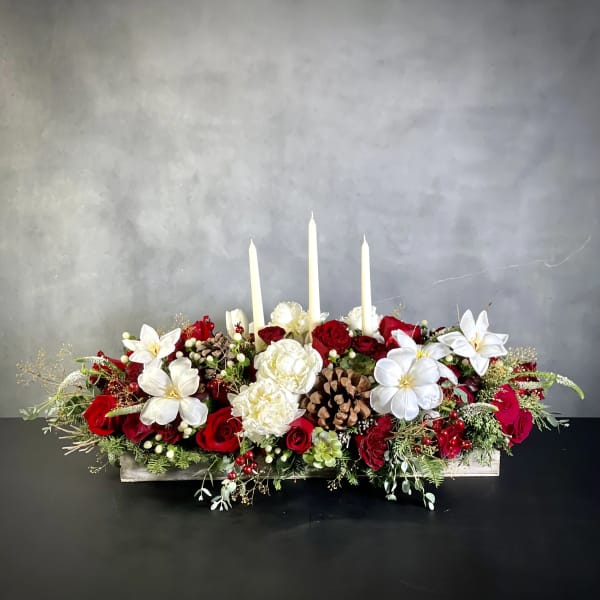 Low floral centerpiece with red and white roses and three white taper candles