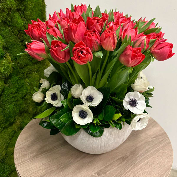 Low white bowl of red tulips with white anemones in a compact arrangement