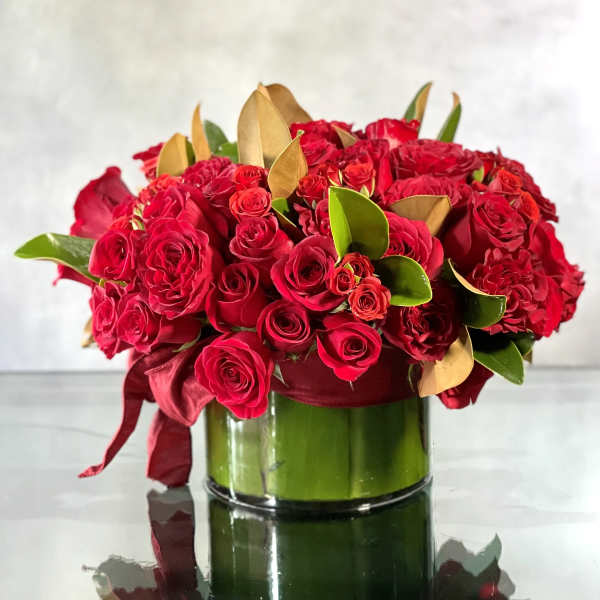 Red rose bouquet in a glass vase with burgundy ribbon