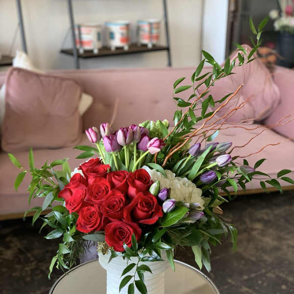 Bouquet of red roses and purple tulips in a white vase