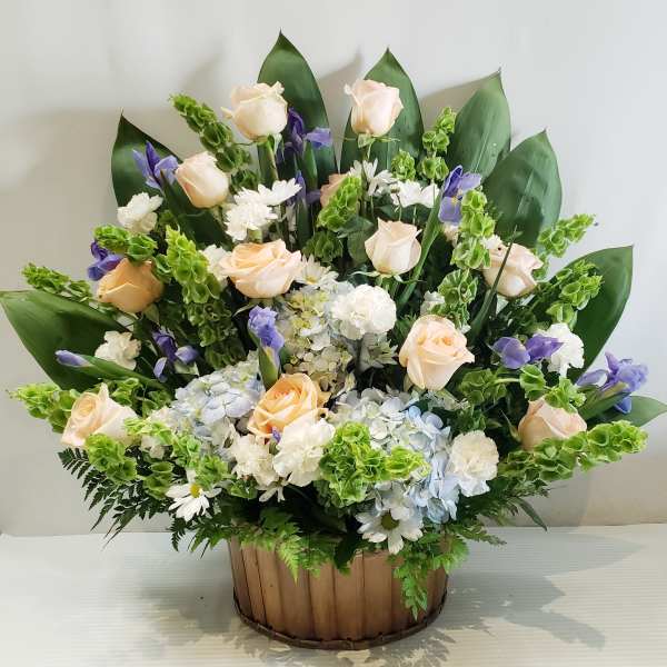 Arrangement of pale roses, white daisies, and purple flowers in a wooden basket