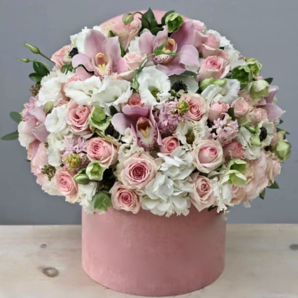 Round arrangement of soft pink and white flowers in a pink hat box container