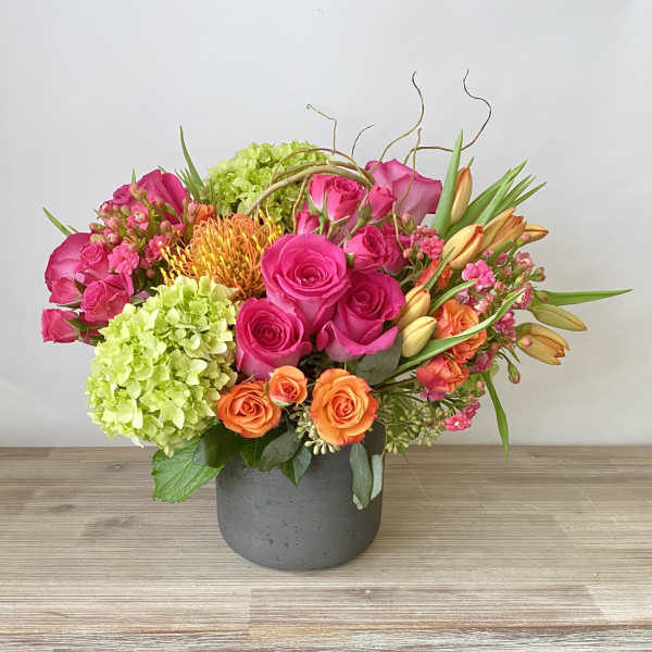 Bright mixed bouquet of pink and orange flowers in a gray vase