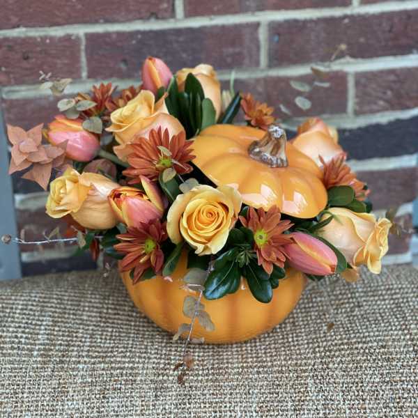 Pumpkin-shaped floral arrangement with yellow roses and orange daisies