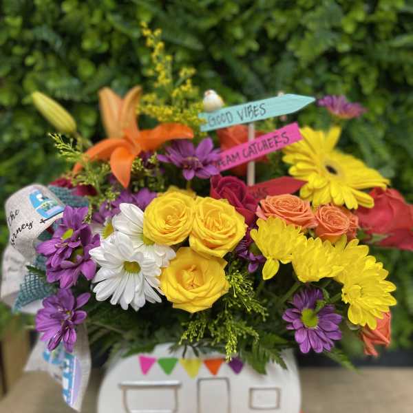 Colorful bouquet in a camper-shaped container with small sign picks