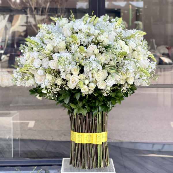Large white floral arrangement with roses and other blooms