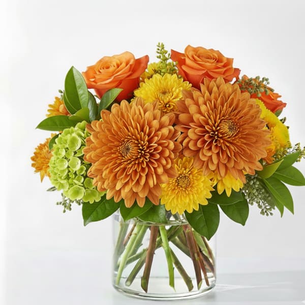 Orange roses and chrysanthemums in a clear glass vase