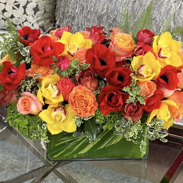 Bright mixed bouquet of red, yellow, and orange flowers in a glass vase