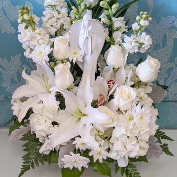 White floral sympathy arrangement with a praying angel figurine