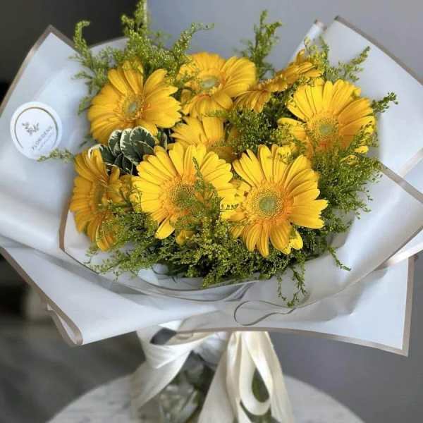 Yellow gerbera daisy bouquet wrapped in white paper