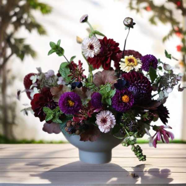 Mixed bouquet of purple, burgundy, and white flowers in a blue vase