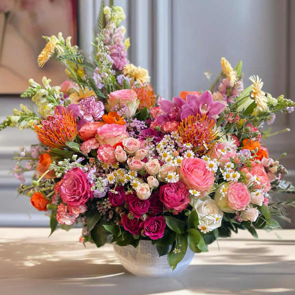 Large mixed flower arrangement in a white bowl vase
