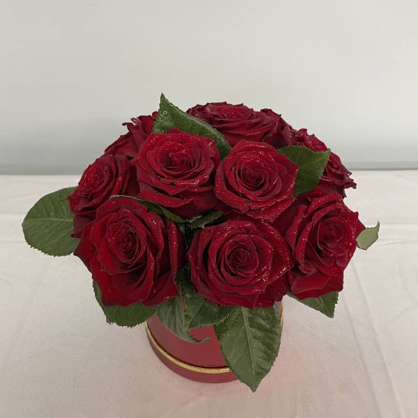 Red roses arranged in a round red box