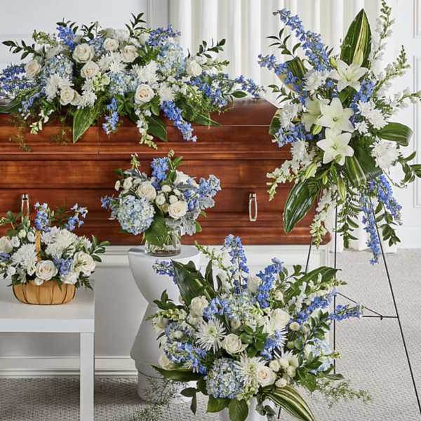 White and blue floral funeral arrangements around a casket