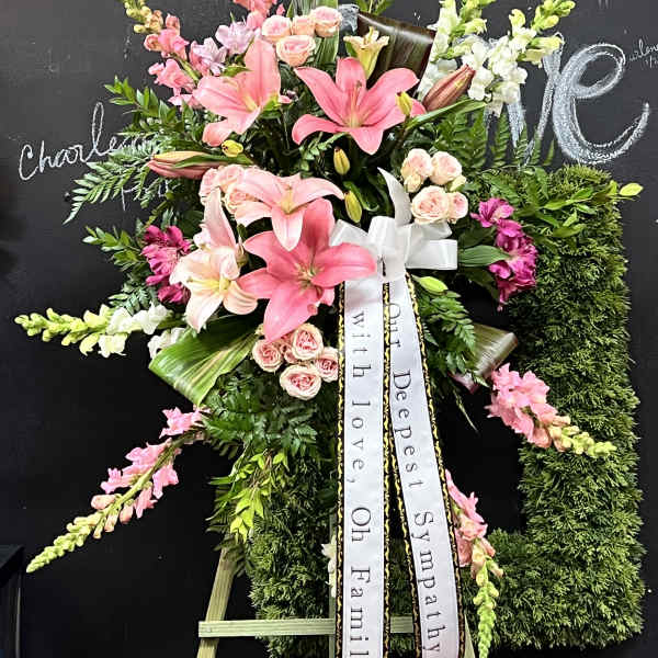 Standing sympathy spray with pink lilies and roses on an easel