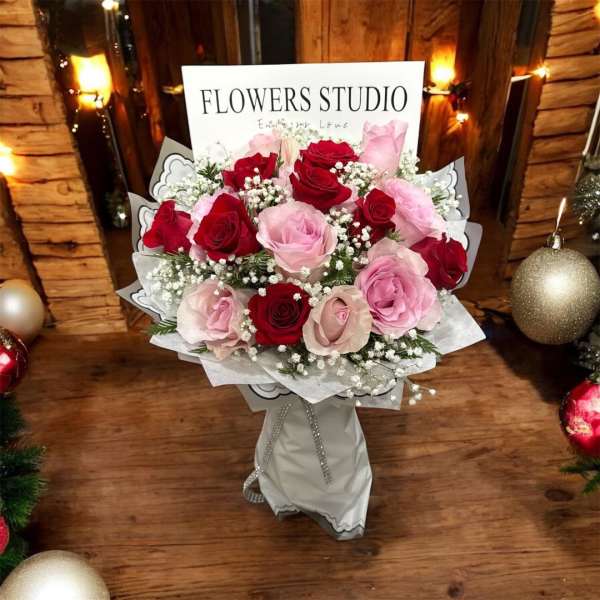 Bouquet of red and pink roses with baby's breath in white wrap