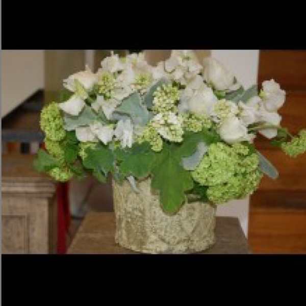 White floral arrangement in a textured vase with green blooms