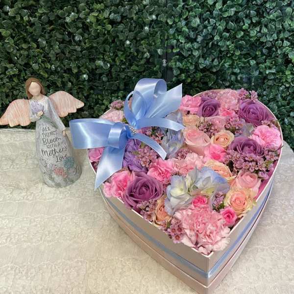 Heart-shaped box of pink and purple roses with a blue ribbon
