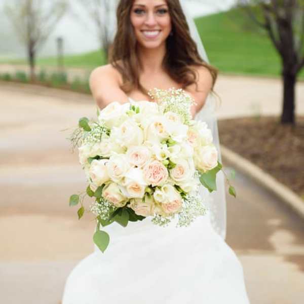 Bride holding a bouquet of white and blush roses