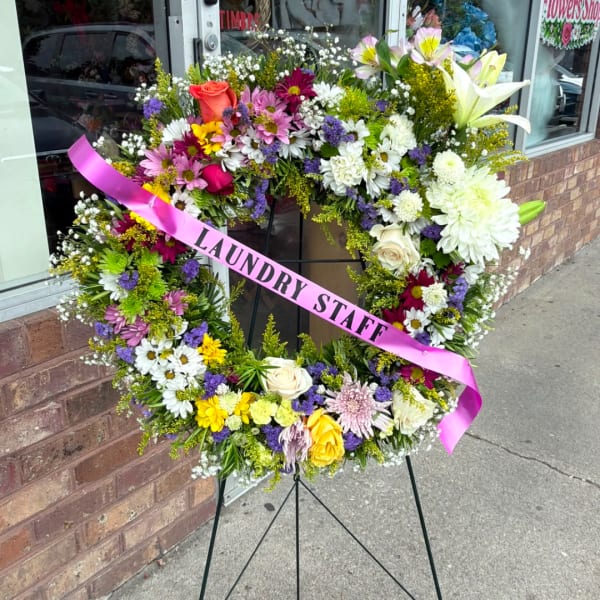 Large floral wreath on an easel with a pink ribbon reading "LAUNDRY STAFF"
