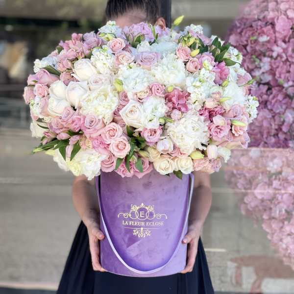 Large bouquet of pink and white roses in a purple hatbox