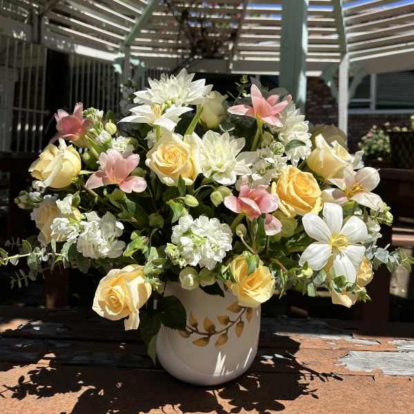Yellow and white roses with pink flowers in a white vase